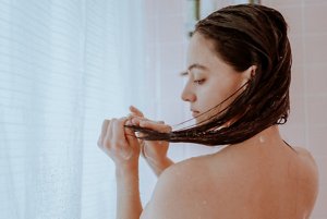 Brunette woman putting conditioner in her hair